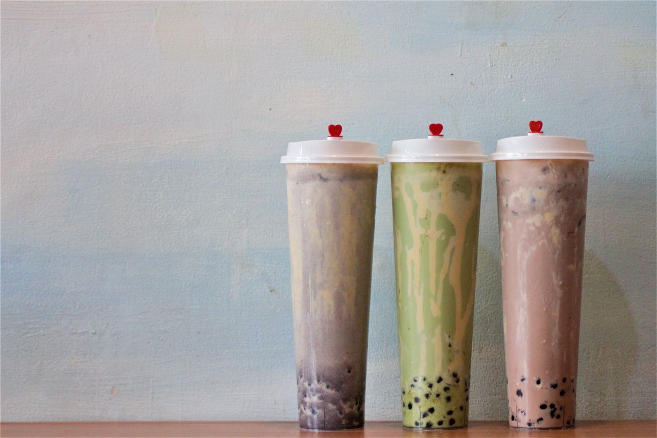 Elegant presentation of three bubble tea flavors in sealed tall cups with red heart lids.