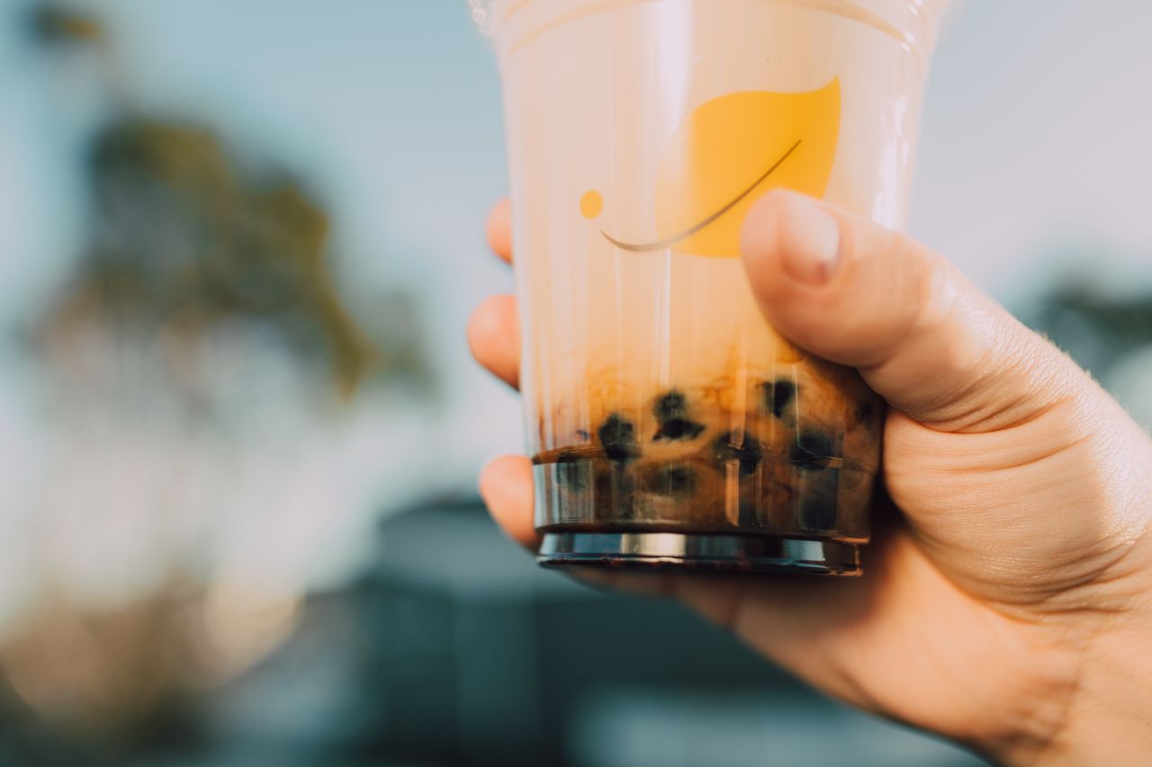 Vibrant image of a hand holding a bubble tea cup with a blurred background. Refreshing and trendy.