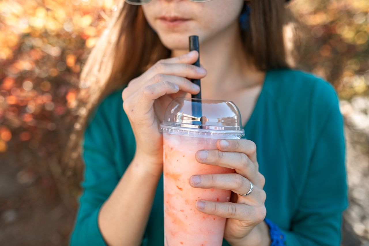Close-up of a woman sipping bubble tea outdoors. Bright and refreshing scene.